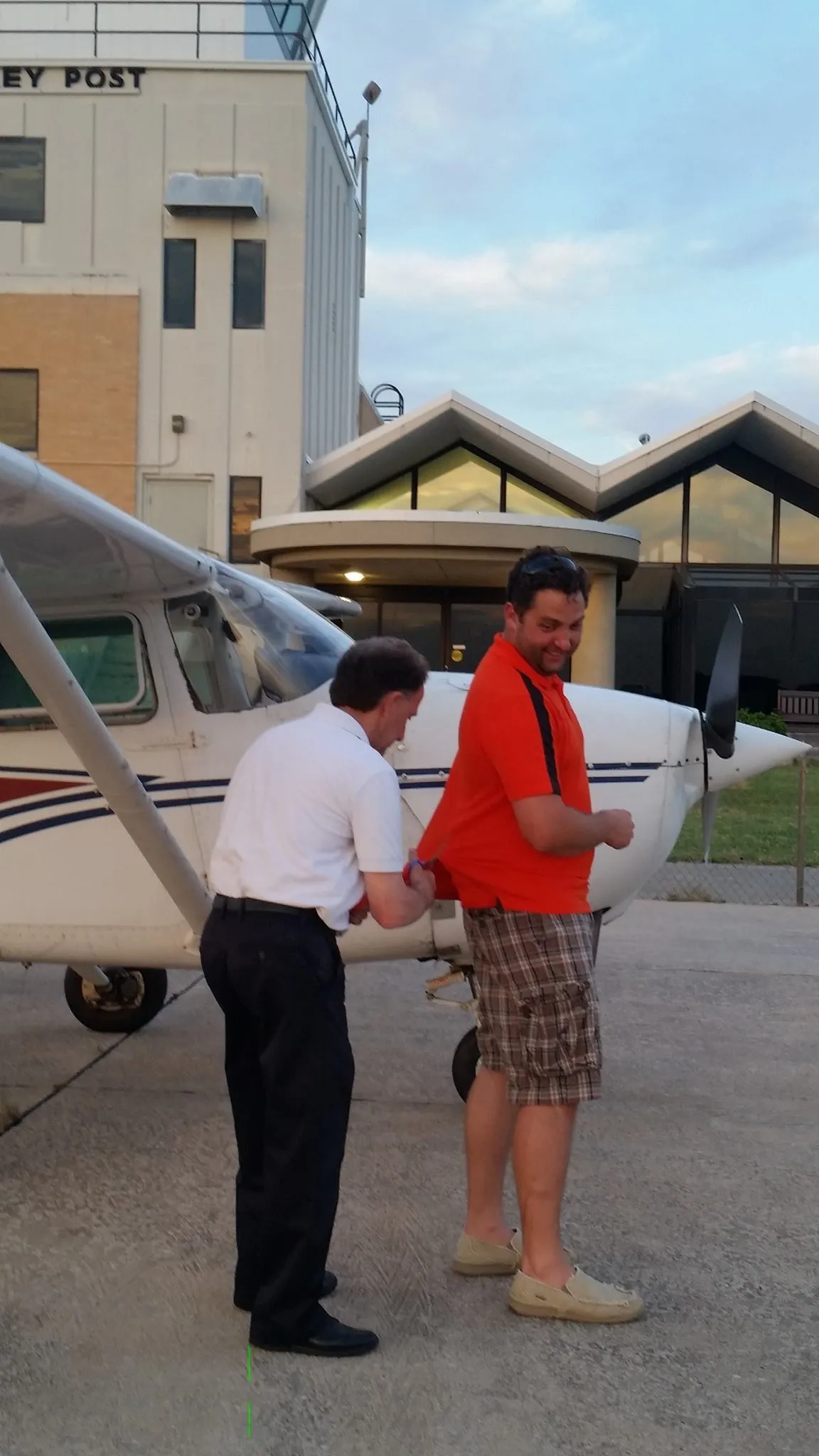 Hal Harris, CFI at ALto Flight Academy Bethany OK cutting t shirt after his student pilot completed his first solo